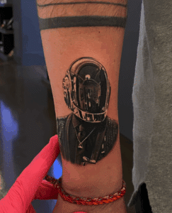 Tattoo of a vintage astronaut helmet on a forearm, showcasing intricate details and shading, emphasizing the artistry of Pony Lawson at Inked Tattoo Studios.